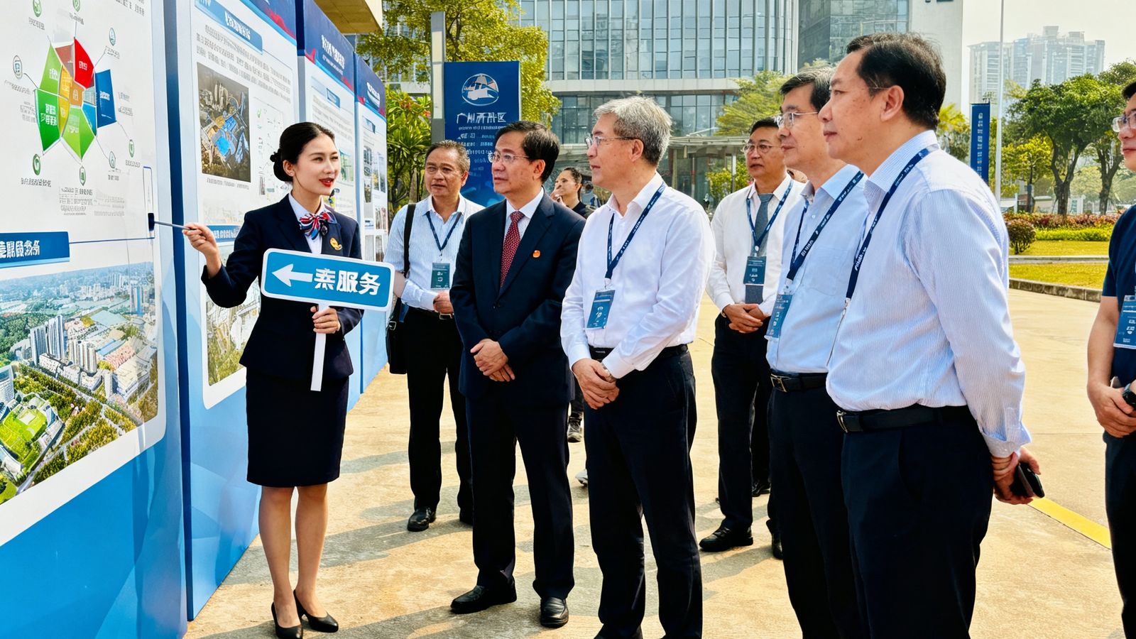 东盟商务考察团在广州开发区参观时，礼宾人员正在进行现场引导服务的实拍场景，考察团成员围在展板前听取介绍